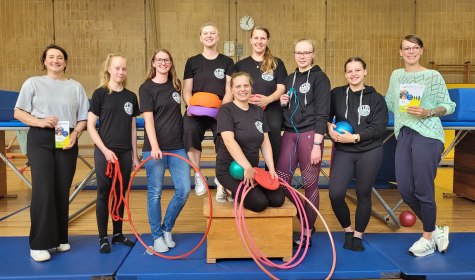 Sportlerinnen und Verwaltungsmitarbeitende sind auf einem Gruppenfoto in einer Turnhalle zu sehen, sie halten Sportgeräte das Programm für Sporteln und Familienspaß 2024 in den Händen, © Stadt Bad Salzuflen