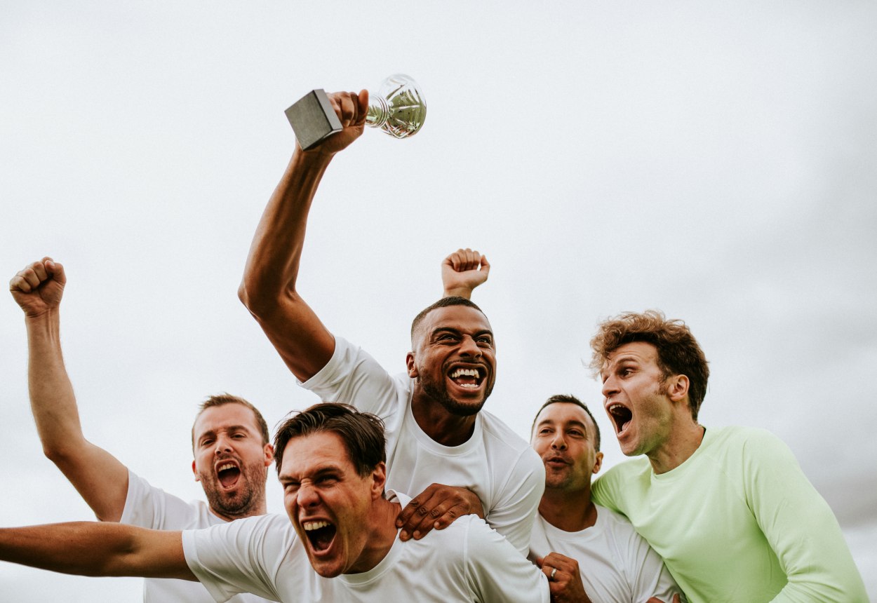 Ein Sportteam feiert den gewonnenen Pokal., © stock.adobe.com - Rawpixel.com