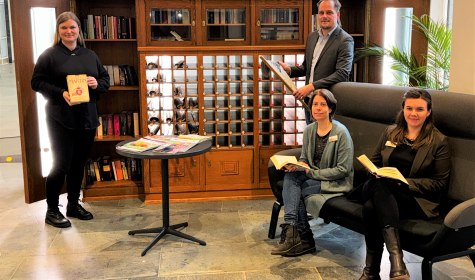 Vier Personen befinden sich vor einem historischen Bücherschrank in der Wandelhalle, © Stadt Bad Salzuflen