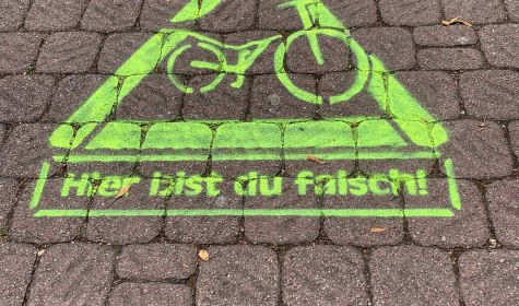 Auf einem Gehweg in Schötmar ist mit neongrüner Farbe ein Geist mit der Aussage &quot;Hier bist du falsch!&quot; aufgesprüht, © Stadt Bad Salzuflen