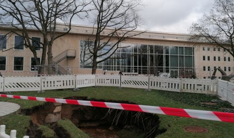 Es ist ein mehrere Quadratmeter großes Loch im Erdreich zu sehen, im Hintergrund befindet sich die Konzerthalle, © Stadt Bad Salzuflen